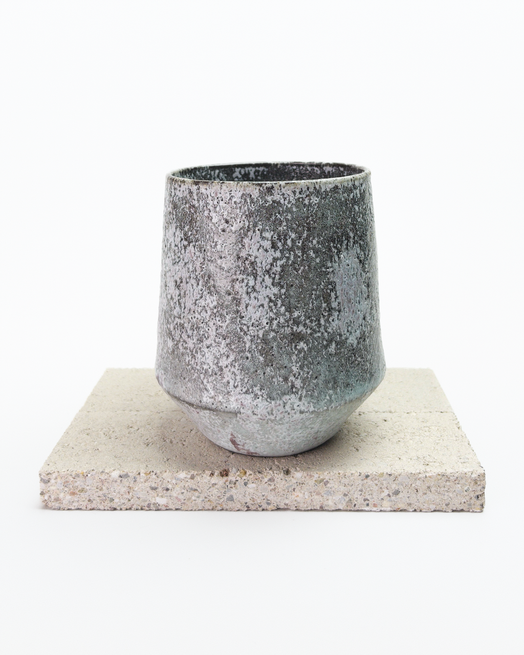 A large gray, shino-glazed mug with moss-like, white glaze patches. Side view with handle hidden behind the mug's body.