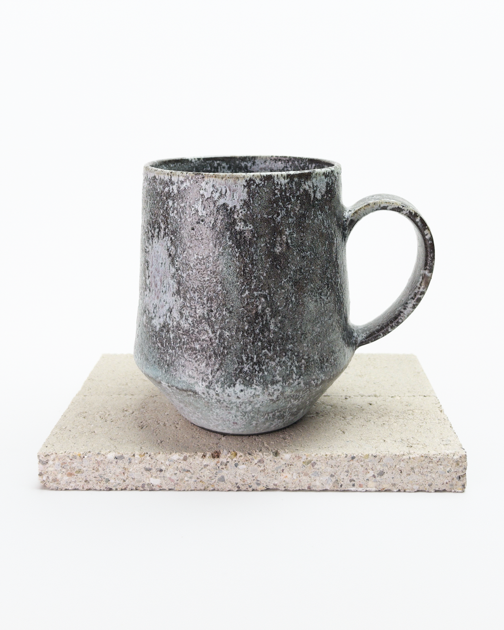 A large gray, shino-glazed mug with moss-like, white glaze patches. Back view with handle to the right.