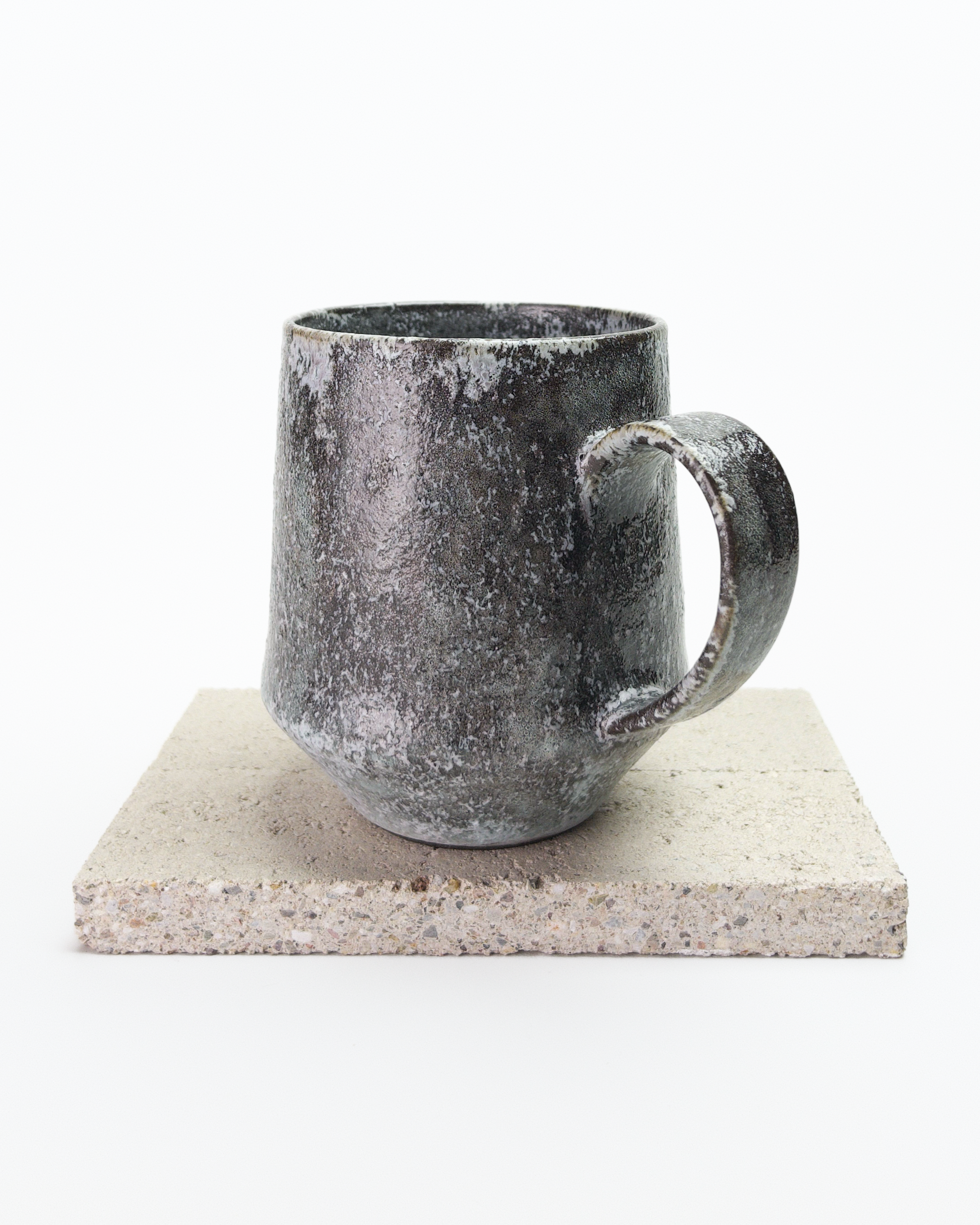 A large gray, shino-glazed mug with moss-like, white glaze patches. Side view with handle postioned at an angle.