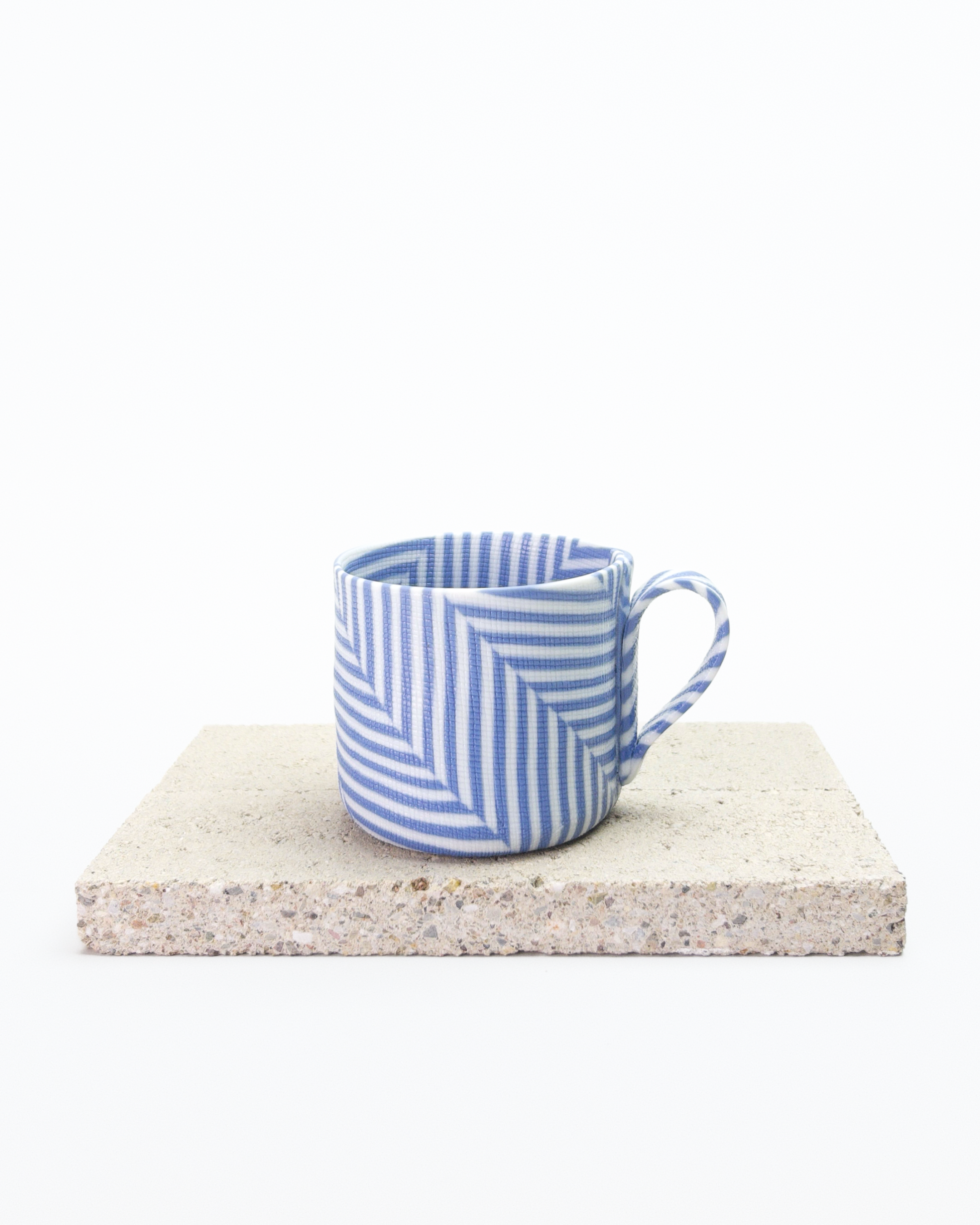 Blue and white striped nerikomi espresso cup on a stone surface