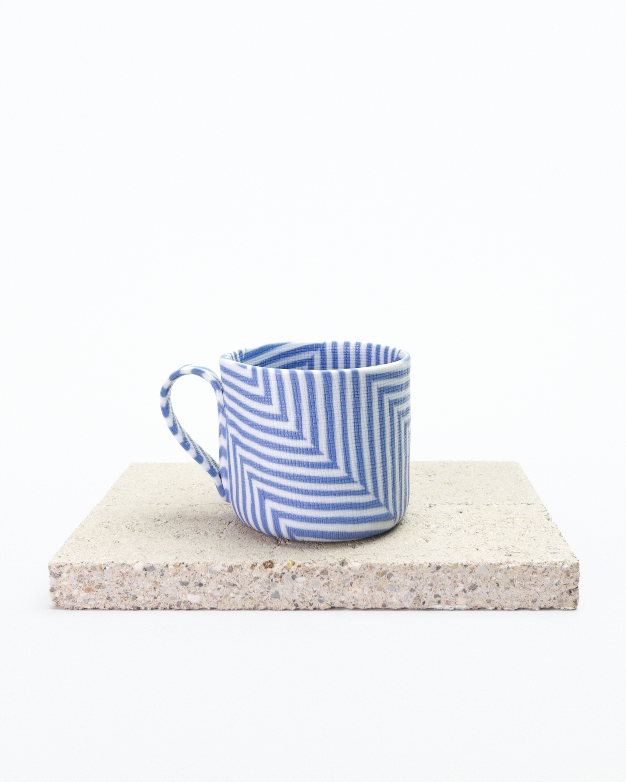 Blue and white striped nerikomi espresso cup on a stone surface