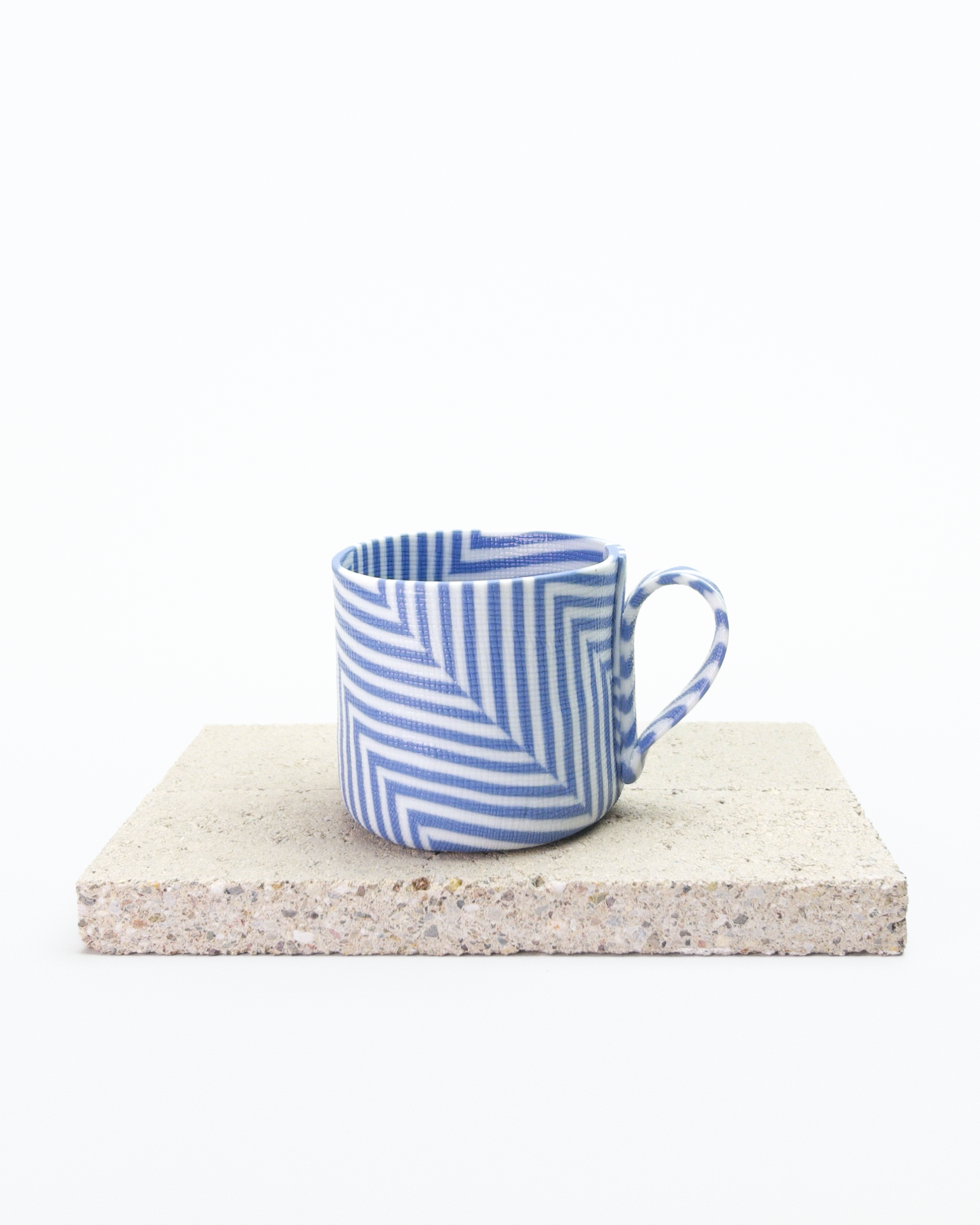 Blue and white striped nerikomi espresso cup on a stone surface