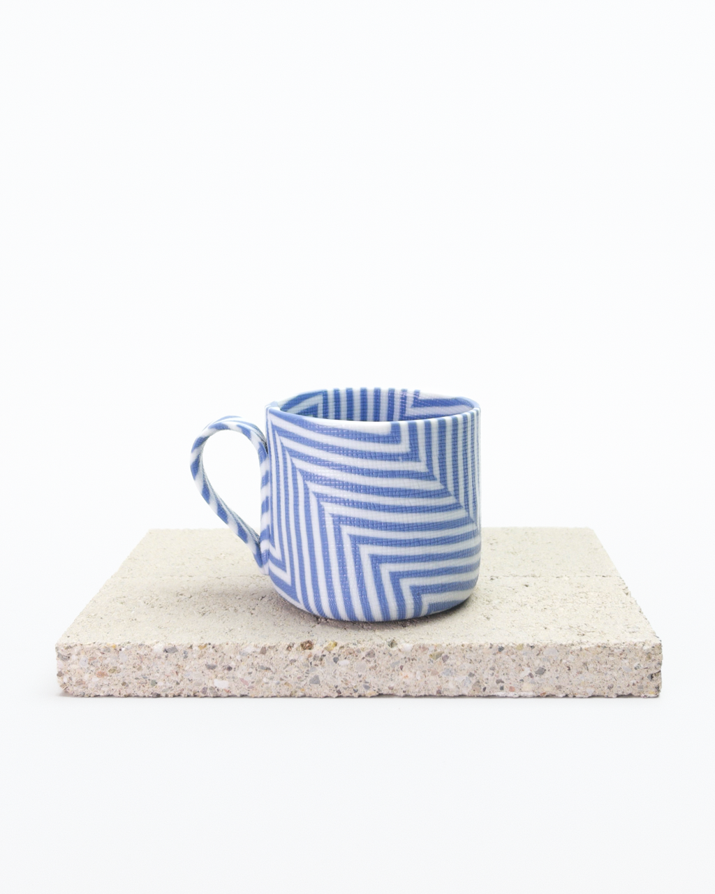 Blue and white striped nerikomi espresso cup on a stone surface