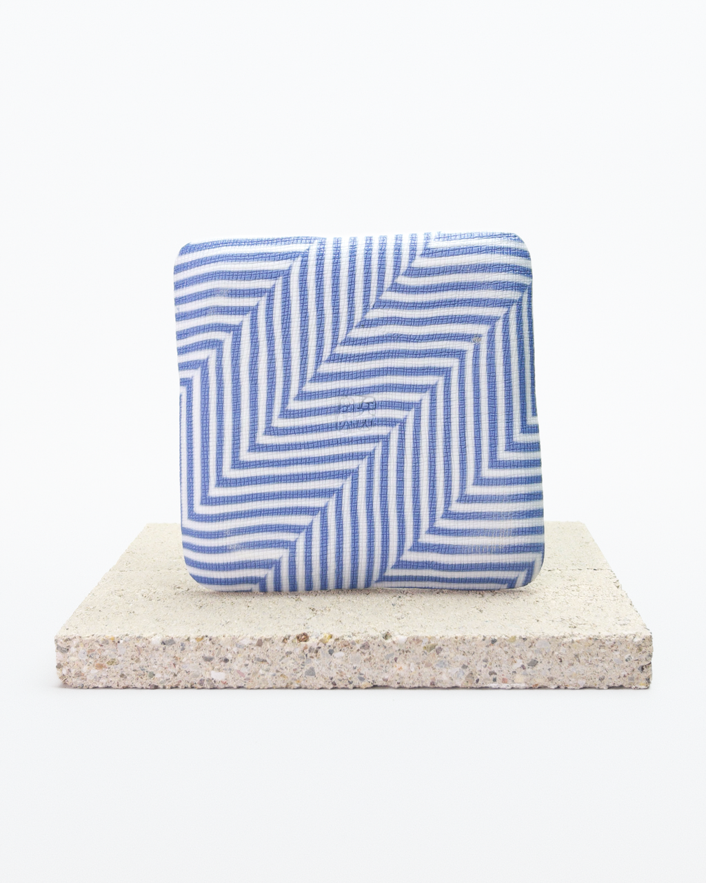 Back side of blue and white striped nerikomi plate with on a beige stone surface