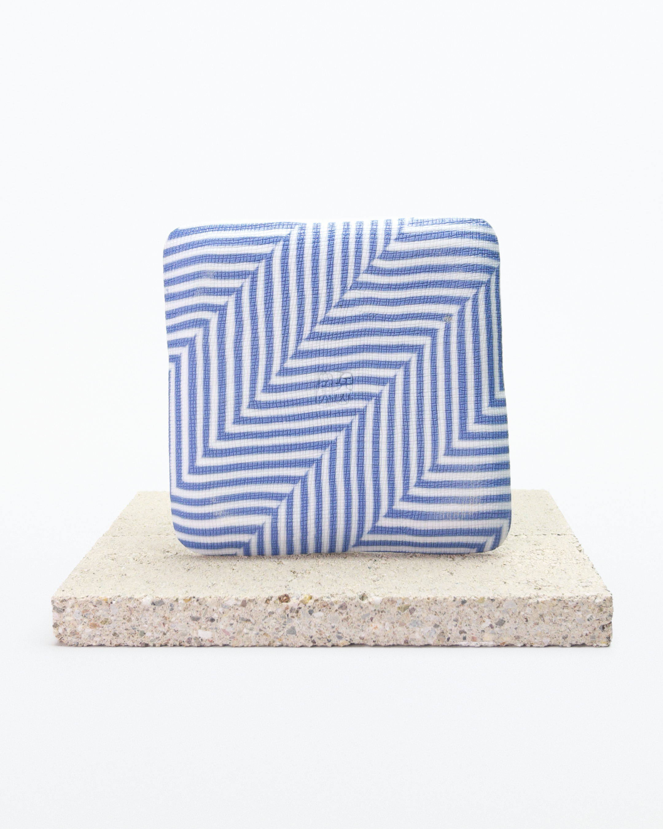Back side of blue and white striped nerikomi plate with on a beige stone surface