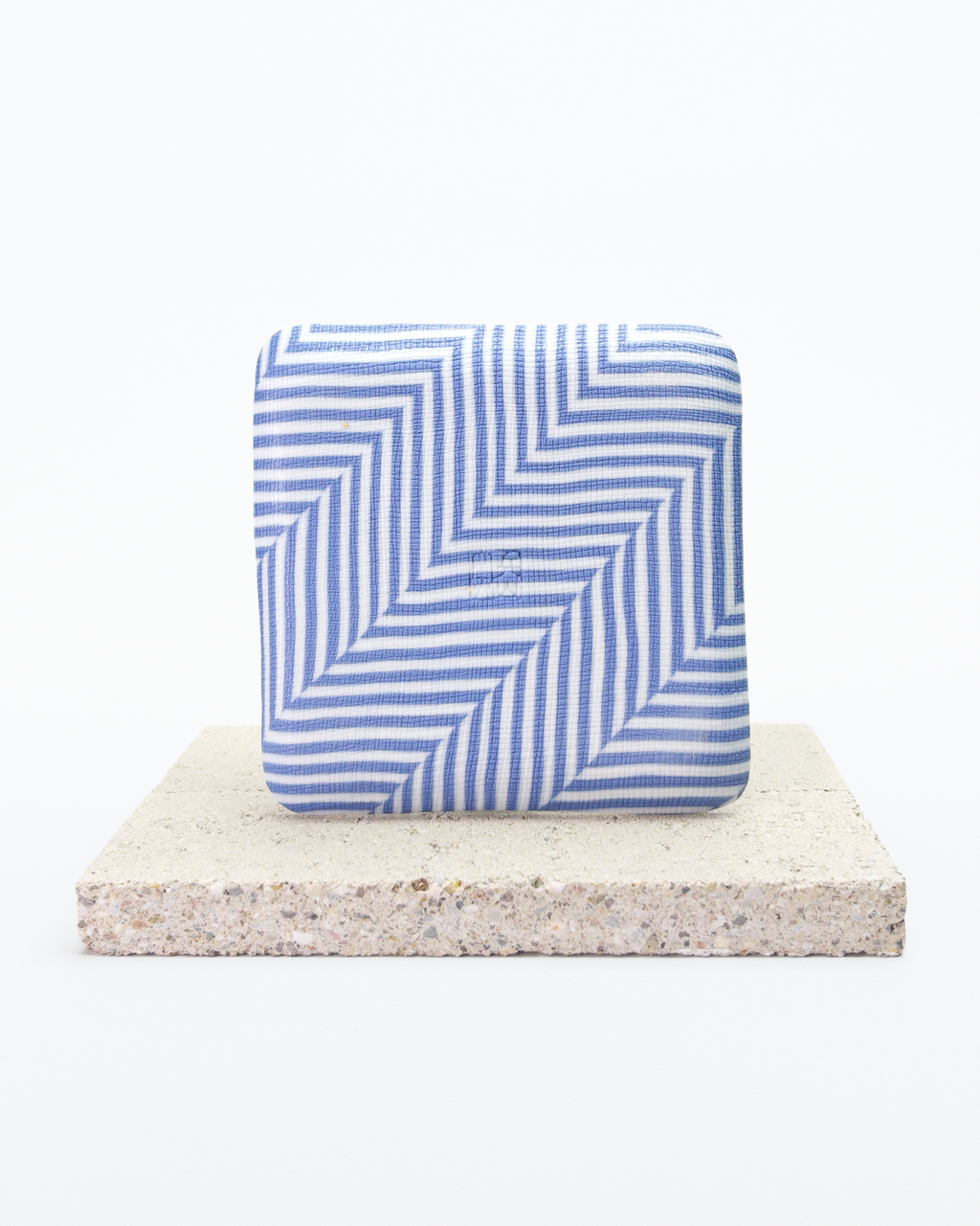 Back side of blue and white striped nerikomi plate with on a beige stone surface