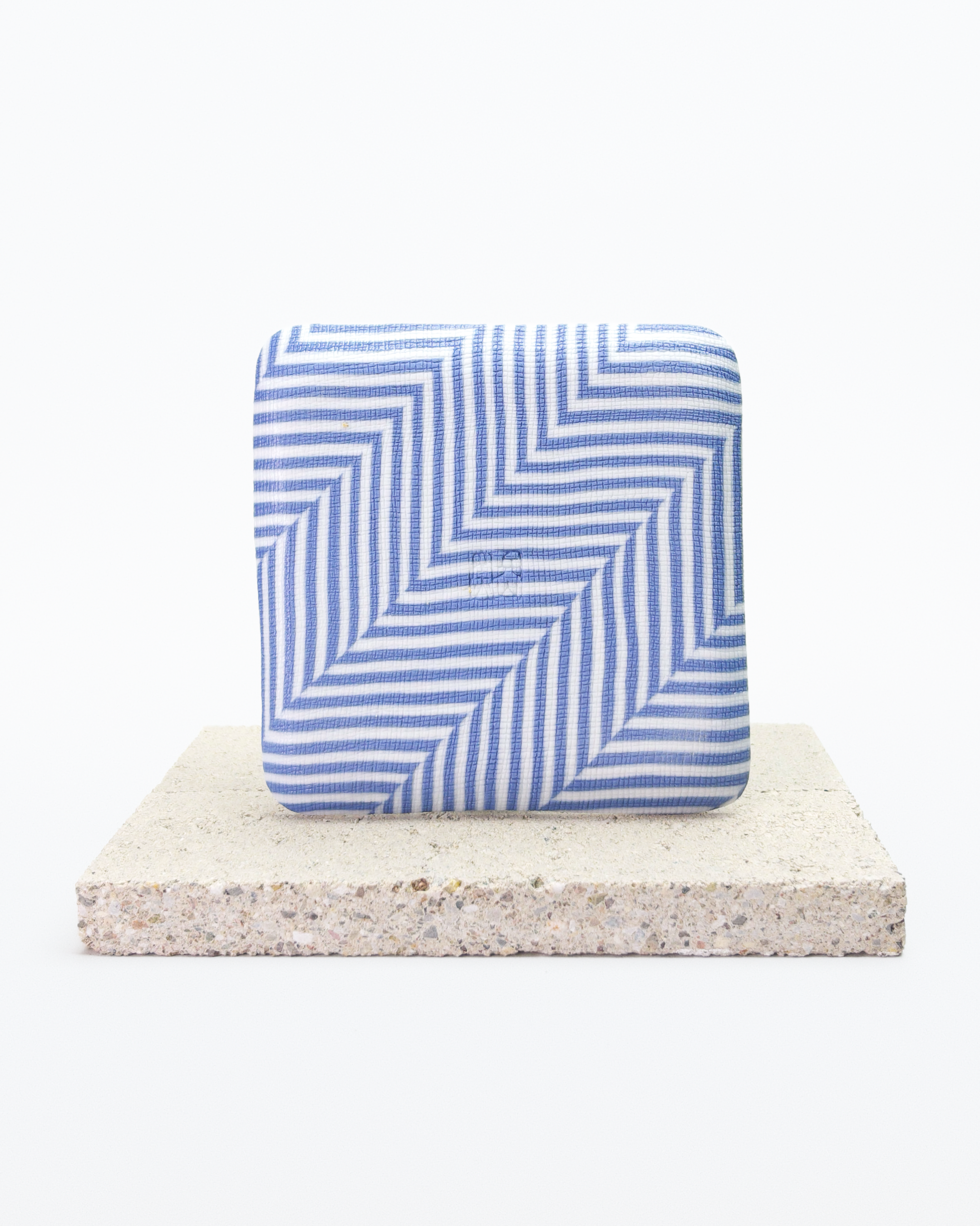 Back side of blue and white striped nerikomi plate with on a beige stone surface