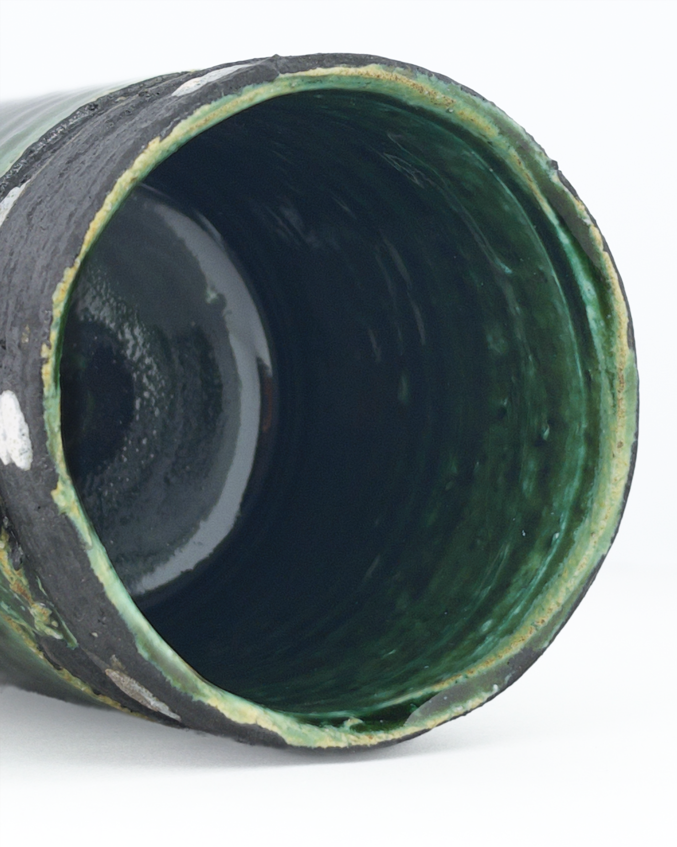 Close-up of a green ceramic mug interior lined with deep green glaze