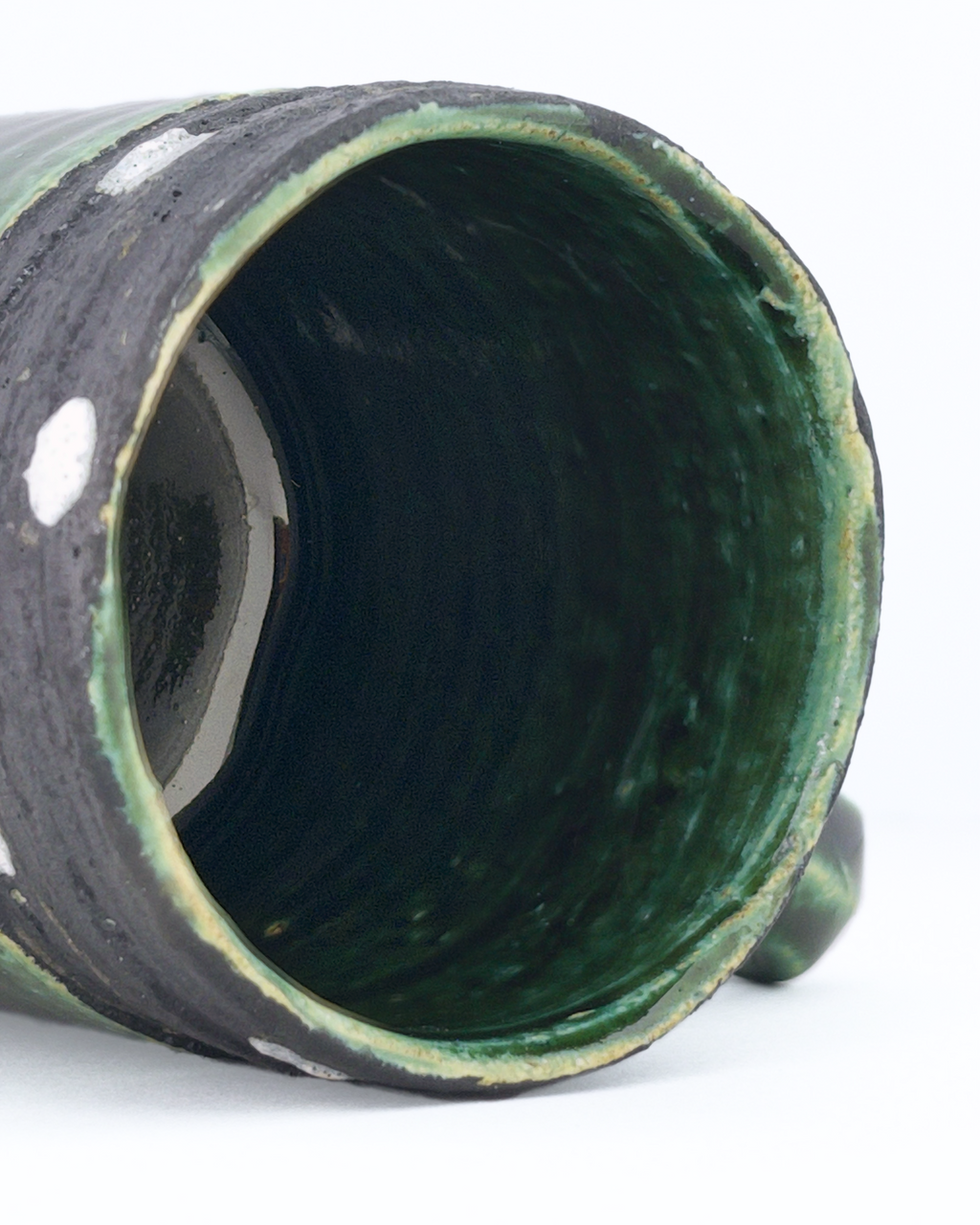 Close-up of a green ceramic mug interior lined with deep green glaze