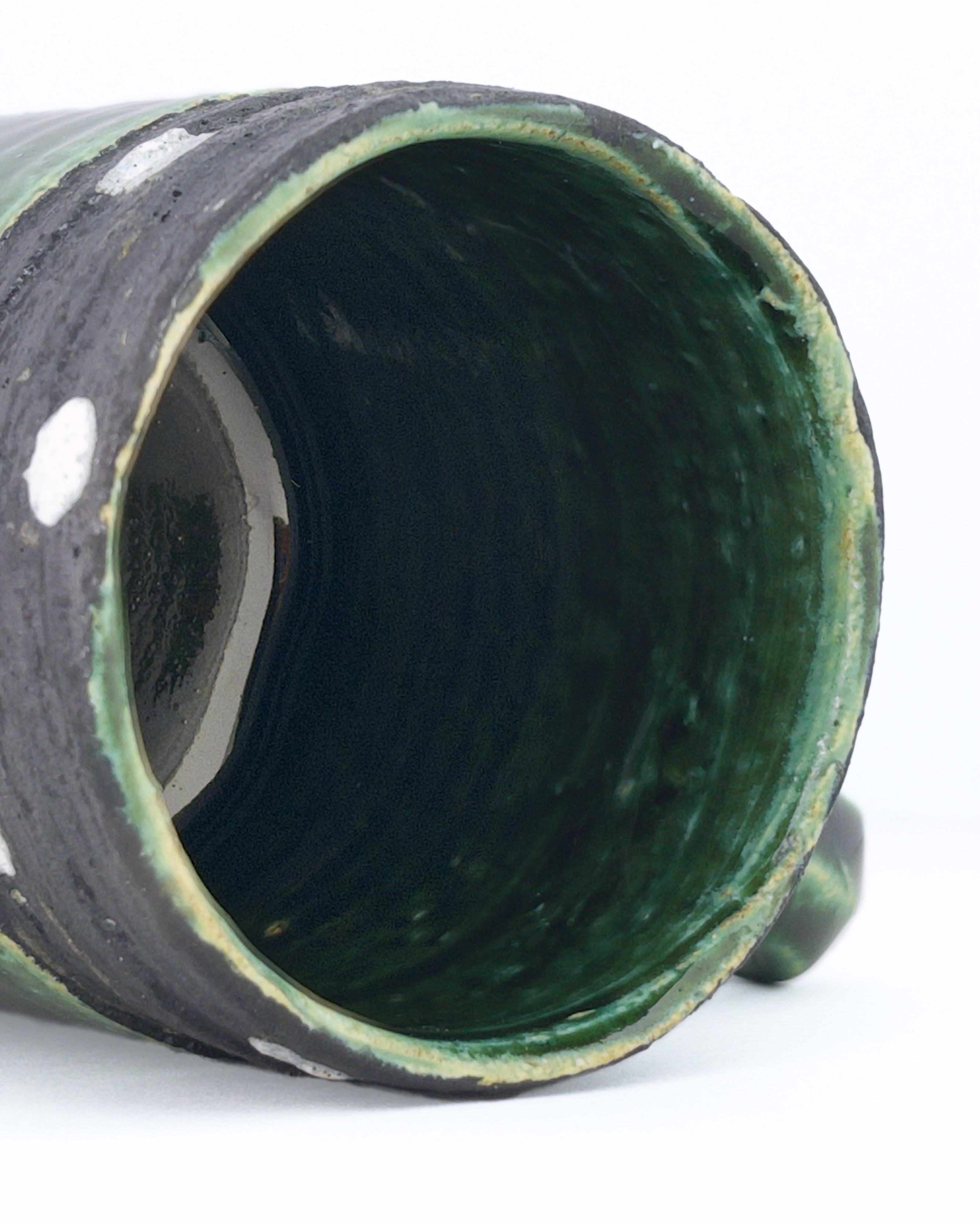 Close-up of a green ceramic mug interior lined with deep green glaze